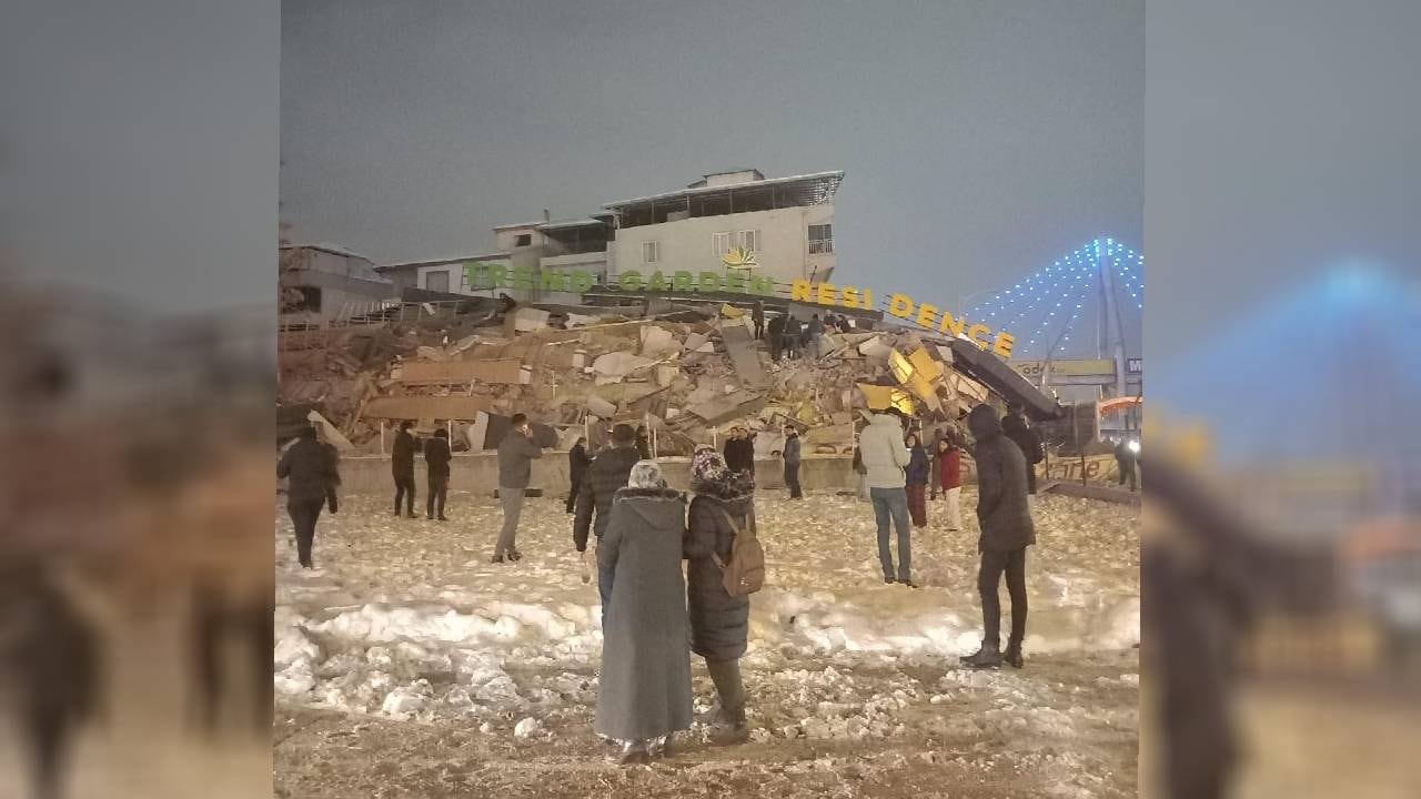 La gente observa un edificio residencial derrumbado después del terremoto.