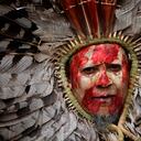 Un indígena con la cara pintada con tinta roja que representa la sangre indígena derramada y la arcilla que representa el oro, participa en una protesta contra el aumento de las actividades mineras que invaden su tierra, frente al Ministerio de Minas y Energía, en Brasilia, Brasil. , lunes 11 de abril de 2022. Foto AP/Eraldo Peres