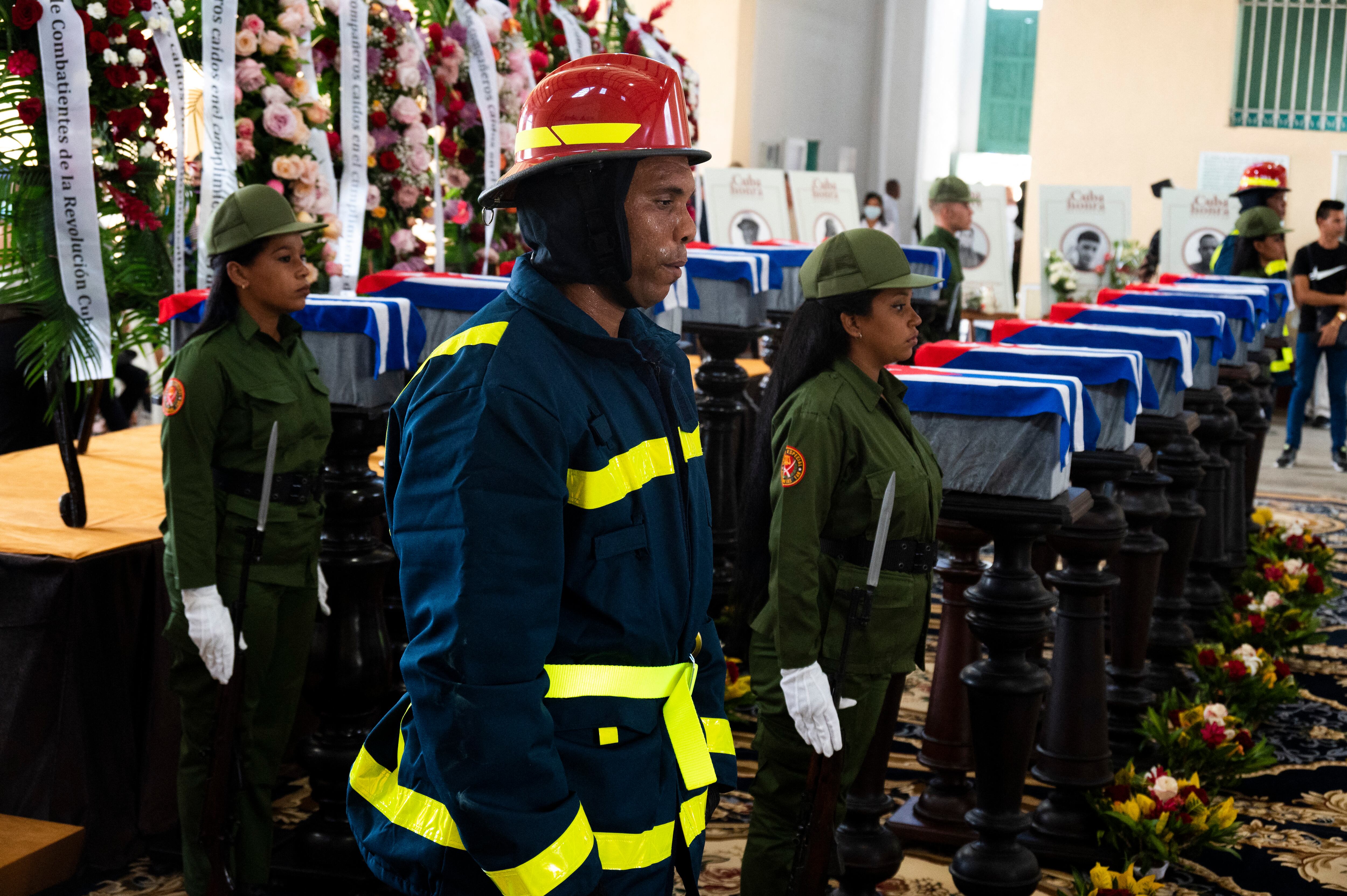 Bomberos y soldados participan en el funeral de 14 bomberos fallecidos en un gran incendio en un depósito de petróleo a principios de agosto, en el Museo de los Bomberos de Matanzas, Cuba, el 19 de agosto de 2022. (Foto de YAMIL LAGE / AFP)