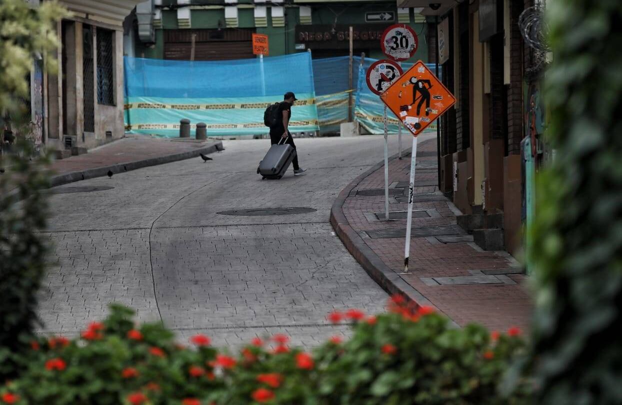 Un hombre con maletas camina por las calles cerca a la estación Aguas de Transmilenio. Foto: Esteban Vega/ Semana.