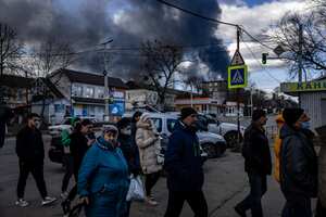 La gente hace fila frente a un supermercado mientras el humo se eleva sobre la ciudad de Vasylkiv, en las afueras de Kiev, el 27 de febrero de 2022, después de que los ataques rusos durante la noche golpearan un depósito de petróleo. (Photo by Dimitar DILKOFF / AFP)