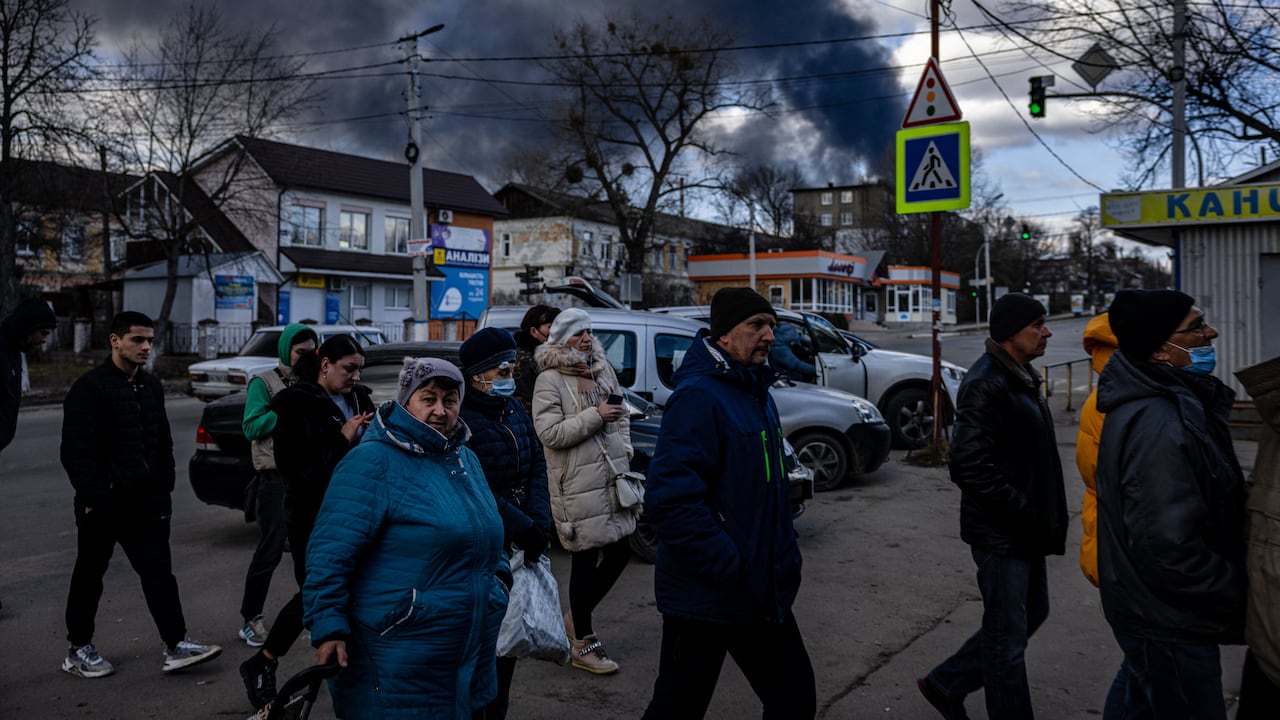 Filas frente a un supermercado mientras el humo se eleva sobre la ciudad de Vasylkov, afueras de Kiev, el 27 de febrero, después de que misil golpeara un depósito de petróleo. (Photo by Dimitar DILKOFF / AFP)