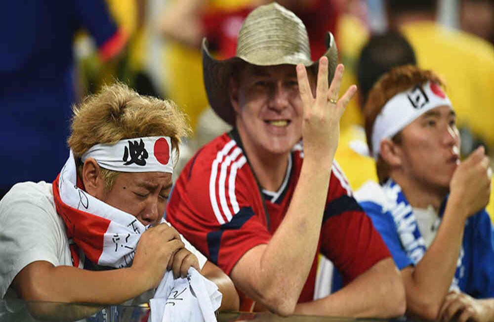 Un fan de Japón se ve abatido mientras un fan de Colombia celebra durante la copa mundo de la FIFA Brazil 2014. Grupo C partido entre Japón y Colombia en el Arena Pantanal en Junio 24, 2014 en Cuiabá, Brasil. Foto: Christopher Lee/Getty