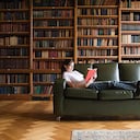 Niña leyendo en un sofá en la biblioteca
