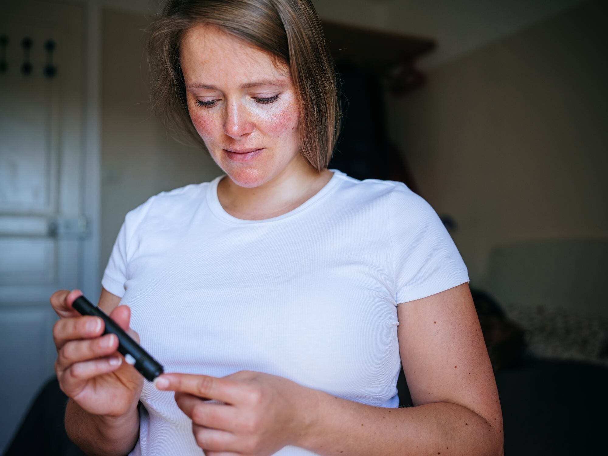Woman doing blood sugar test at home.