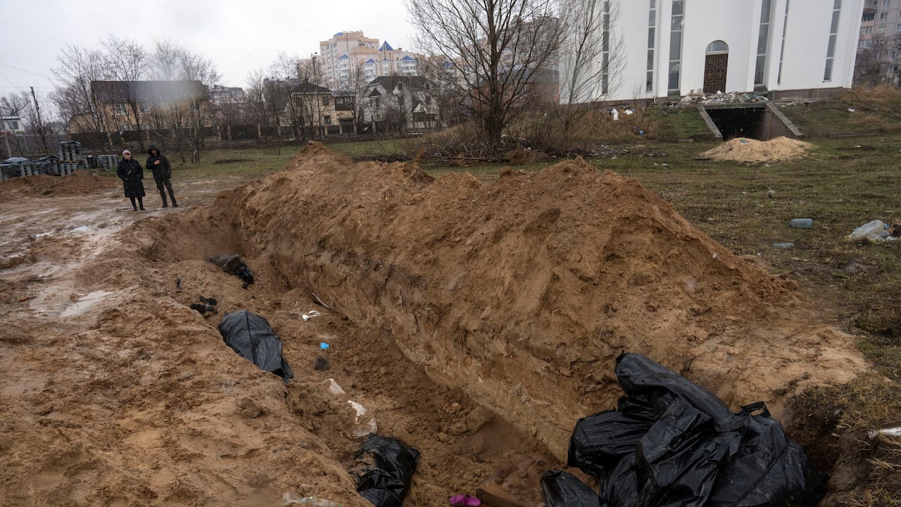 Los vecinos se reúnen junto a una fosa común en Bucha, en las afueras de Kiev, Ucrania, el domingo 3 de abril de 2022.