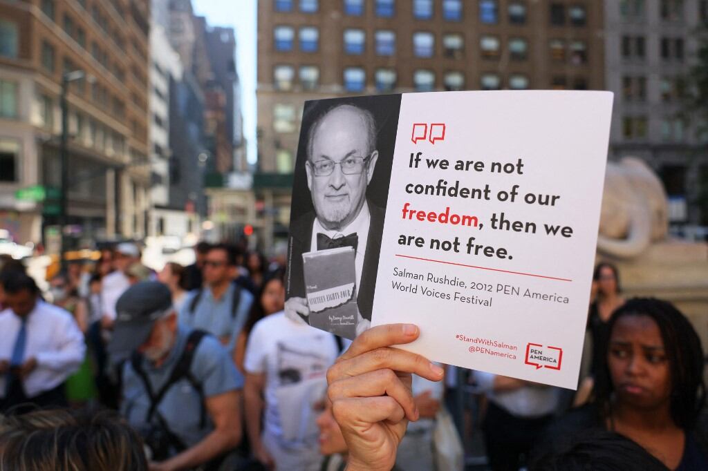 Las personas sostienen carteles mientras se reúnen en los escalones de la Biblioteca Pública de Nueva York para mostrar su apoyo a Salman Rushdie el 19 de agosto de 2022 en la ciudad de Nueva York. La comunidad literaria de Nueva York se reunió en la Biblioteca Pública de Nueva York en solidaridad con Salman Rushdie una semana después de que fuera atacado y apuñalado varias veces mientras daba una charla en la Institución Chautauqua. Su atacante se declaró inocente el jueves de los cargos de intento de asesinato en segundo grado y asalto en segundo grado. Michael M. Santiago/Getty Images/AFP (Foto de Michael M. Santiago / GETTY IMAGES NORTH AMERICA / Getty Images vía AFP)