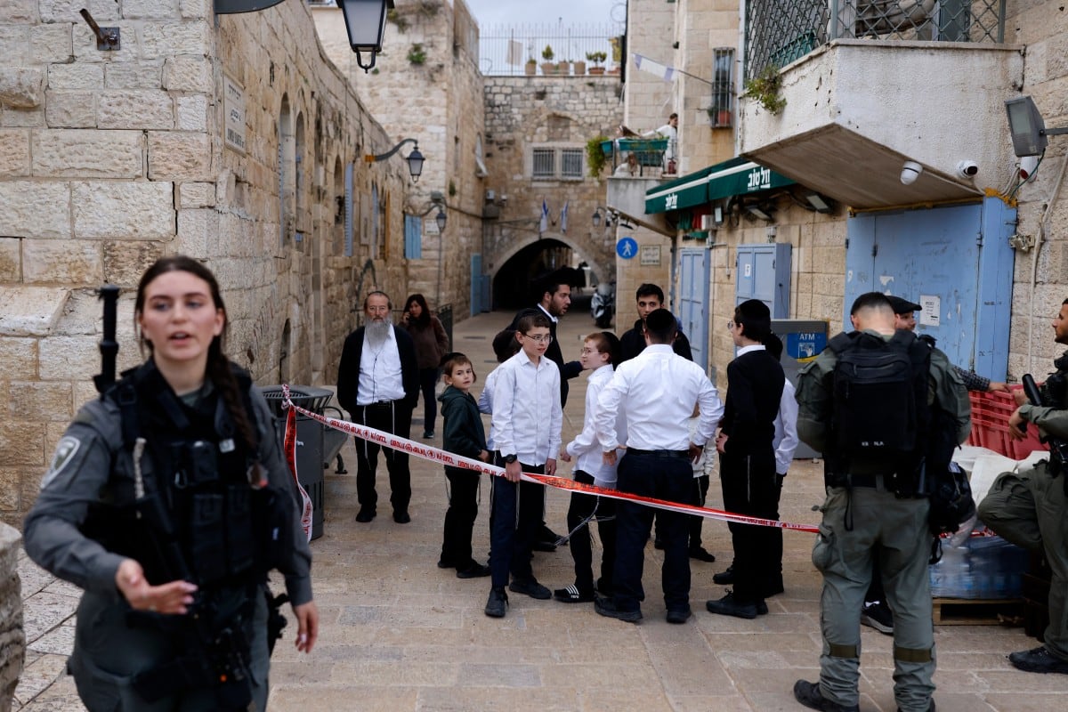 Los israelíes religiosos se encuentran detrás de la cinta mientras observan el impacto o los restos de un proyectil interceptado que cayó dentro de los muros de la Ciudad Vieja de Jerusalén el 20 de marzo de 2026, mientras los ciudadanos musulmanes celebran el Eid al-Fitr que marca el final del mes sagrado del Ramadán. Los lugares sagrados en la antigua ciudad ocupada de Jerusalén oriental han permanecido cerrados por razones de seguridad desde el estallido de la guerra de Medio Oriente el 28 de febrero, cuando Israel y Estados Unidos lanzaron ataques contra Irán, matando a su líder supremo y provocando ataques de represalia de la República Islámica contra Israel y a través del Golfo