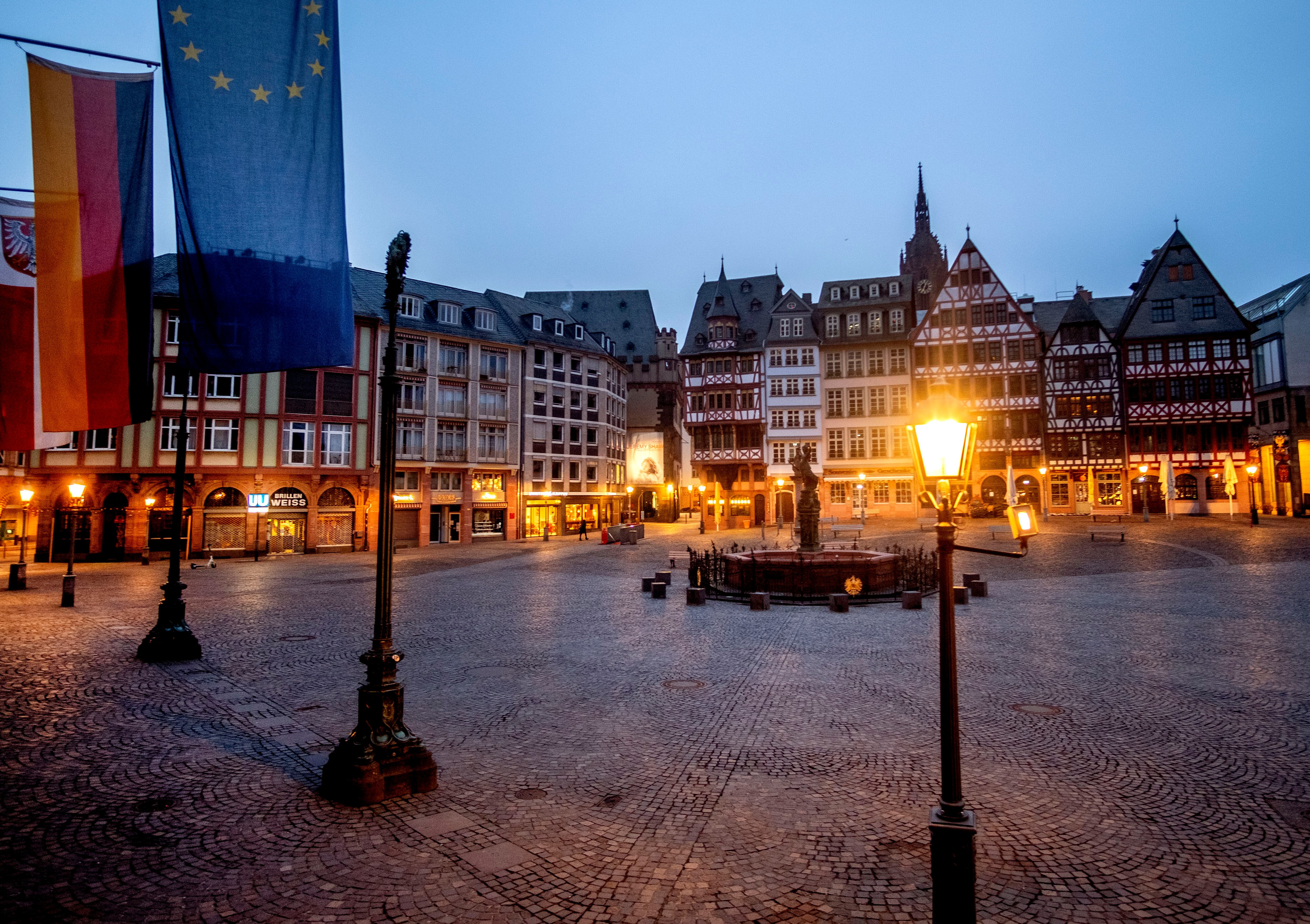 La plaza Roemerberg está vacía en Frankfurt, Alemania, la madrugada del martes 9 de marzo de 2021. Una bandera alemana y una europea están fijadas en el ayuntamiento de la izquierda. (Foto AP / Michael Probst)