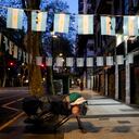 Una persona sin hogar duerme en una cama improvisada montada con un carro de la compra y un banco de la calle, en una zona decorada con banderas de Argentina, en Buenos Aires, Argentina, el miércoles temprano 27 de septiembre de 2023. (AP Foto/Natacha Pisarenko)
