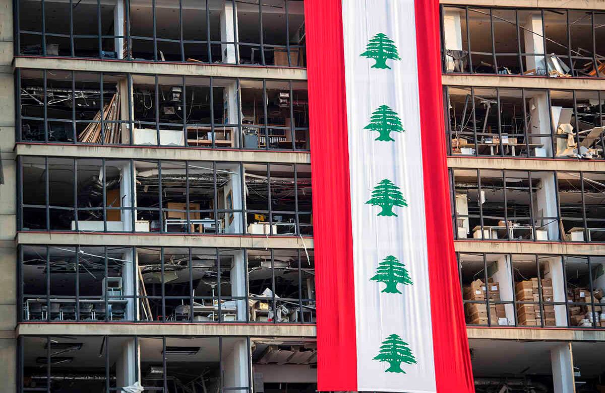 Una pancarta con representaciones de la bandera libanesa cuelga de un edificio dañado en un vecindario cercano al sitio de la explosión que la semana pasada golpeó el puerto marítimo de Beirut, Líbano. Imagen del 12 de agosto. Foto: Hassan Ammar / AP Photo  