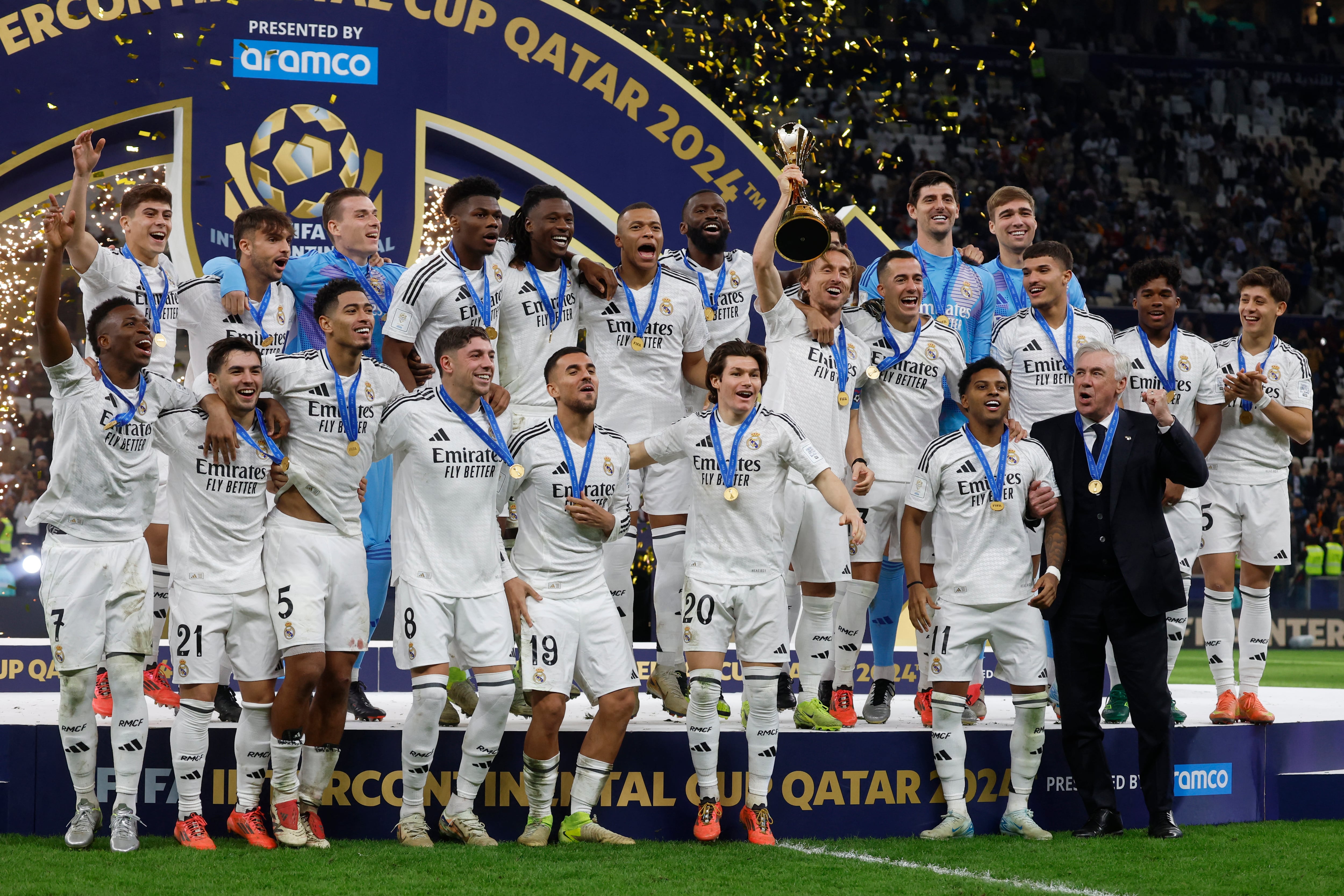 El entrenador italiano del Real Madrid, Carlo Ancelotti, y sus jugadores celebran en el podio tras ganar el partido de fútbol de la final de la Copa Intercontinental de la FIFA 2024 contra el Pachuca mexicano en el estadio Lusail de Doha el 18 de diciembre de 2024.