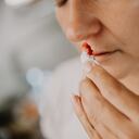 Woman wiping her bleeding nose with tissue