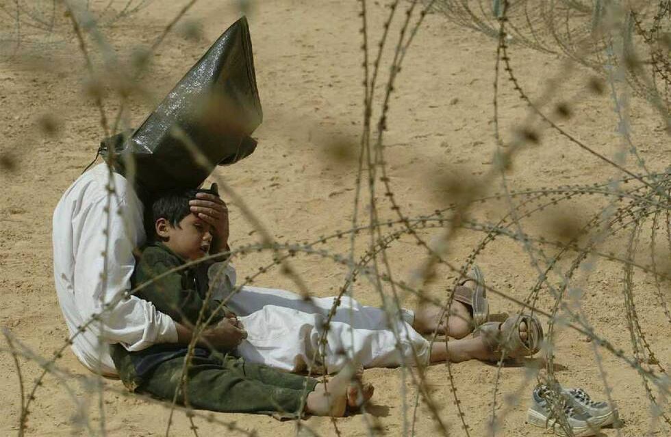En esta fotografía la imagen de un hombre iraquí detenido con la cabeza cubierta, consolando a su hijo de cuatro años, en el campo de prisioneros de guerra estadounidense de Nayaf sur de la capital Bagdad en Irak. Esta fotografía del 31 de Marzo de 2003 fue la ganadora como mejor imagen periodística de ese año. Una década después salieron a la luz imágenes de torturas y abusos en contra de prisioneros en la cárcel de Abu Ghraib, un escándalo que envolvió a personal de los Estados Unidos involucrados en la ocupación. Foto: EFE/ Al Iraquiya.