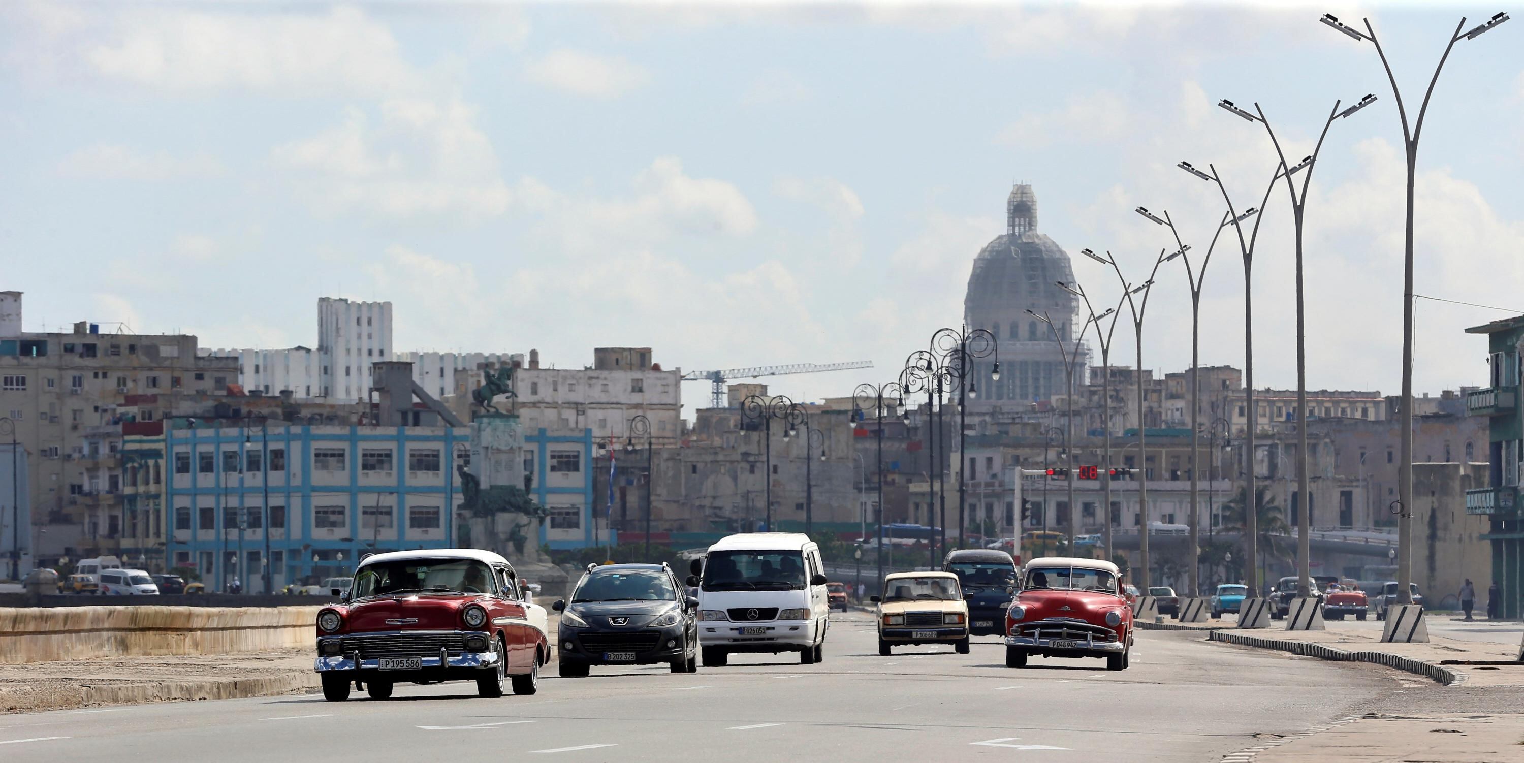 Varios autos pasan por el malecón en La Habana (Cuba).
