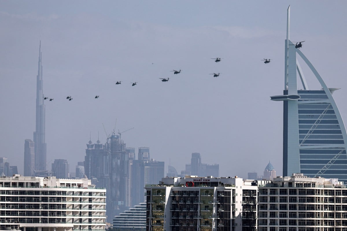 Helicópteros del ejército de los Emiratos Árabes Unidos vuelan desde el hotel Burj al Arab (R) hacia Burj Khalifa, en Dubai, el 16 de enero de 2026. (Foto de Fadel SENNA / AFP)