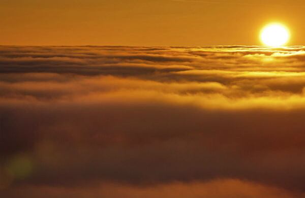 Esta fotografía muestra una puesta de sol con la niebla que cubre la montaña de Klinovec en República Checa y la montaña de Fichtelberg en Alemania. (EFE)