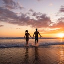 Pareja saliendo del océano al atardecer en Costa Rica.