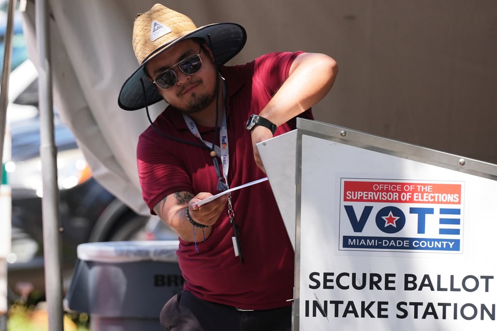 Un trabajador electoral deposita una boleta de voto por correo en un contenedor seguro en la oficina del Supervisor de Elecciones del condado de Miami-Dade, durante las elecciones primarias de Florida en Doral, Florida, el martes 18 de agosto de 2026. (Foto AP/Lynne Sladky)