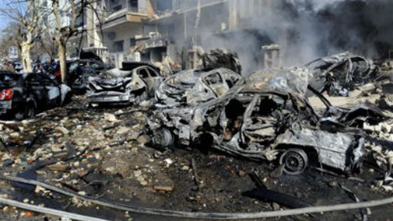 Esta foto de la agencia oficial siria SANA, muestra carros destruídos y destrucción cerca de el departamento de inteligencia aérea, objeto del atentado del sábado.