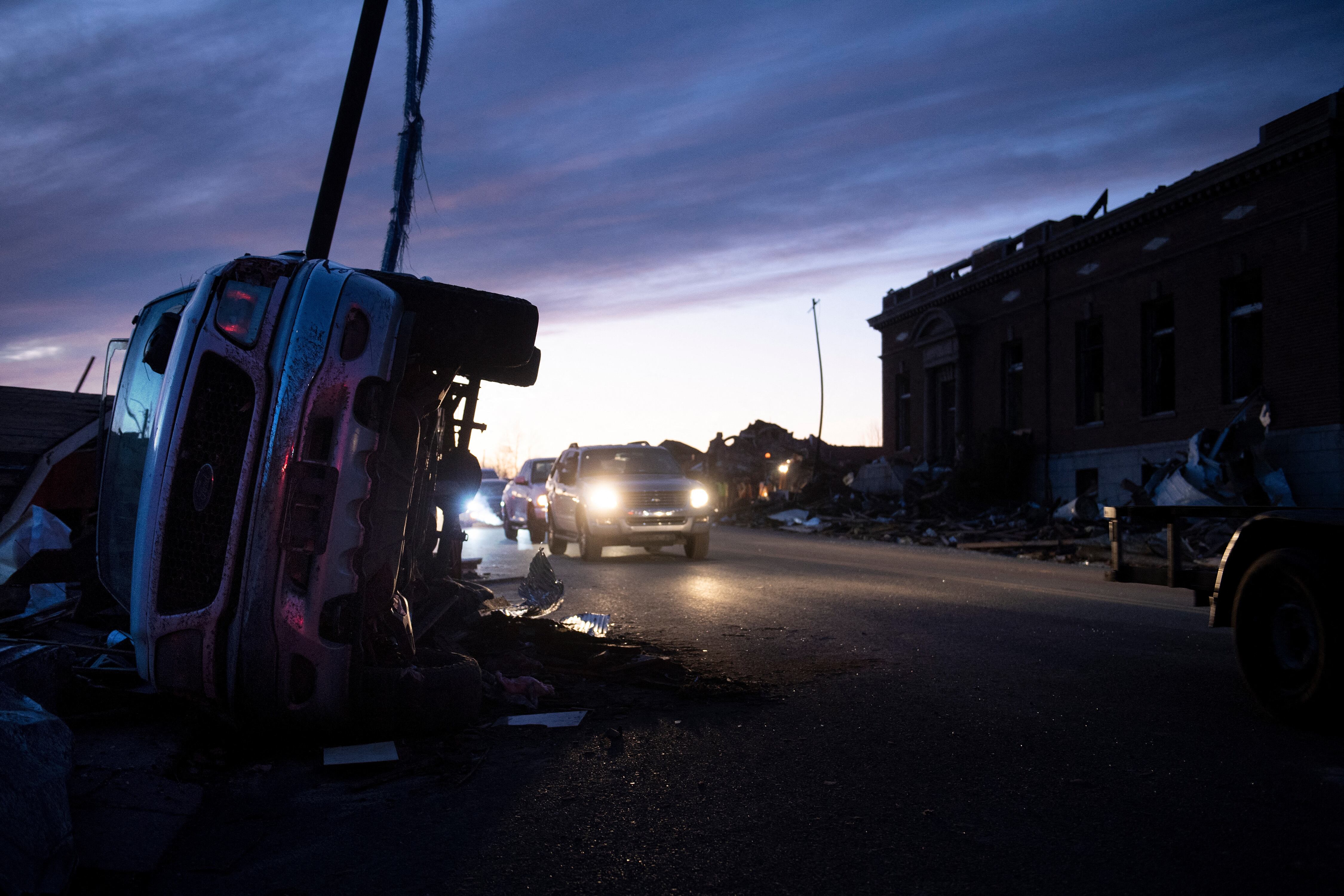 Los automóviles y camiones se abren camino más allá de los daños causados ​​por el tornado después de que el clima extremo azotara la región el 11 de diciembre de 2021 en Mayfield, Kentucky. - Docenas de devastadores tornados arrasaron cinco estados de EE. UU. Durante la noche, dejando más de 80 personas muertas el sábado en lo que el presidente Joe Biden dijo que fue "uno de los brotes de tormenta más grandes" de la historia. (Foto de Brendan Smialowski / AFP)