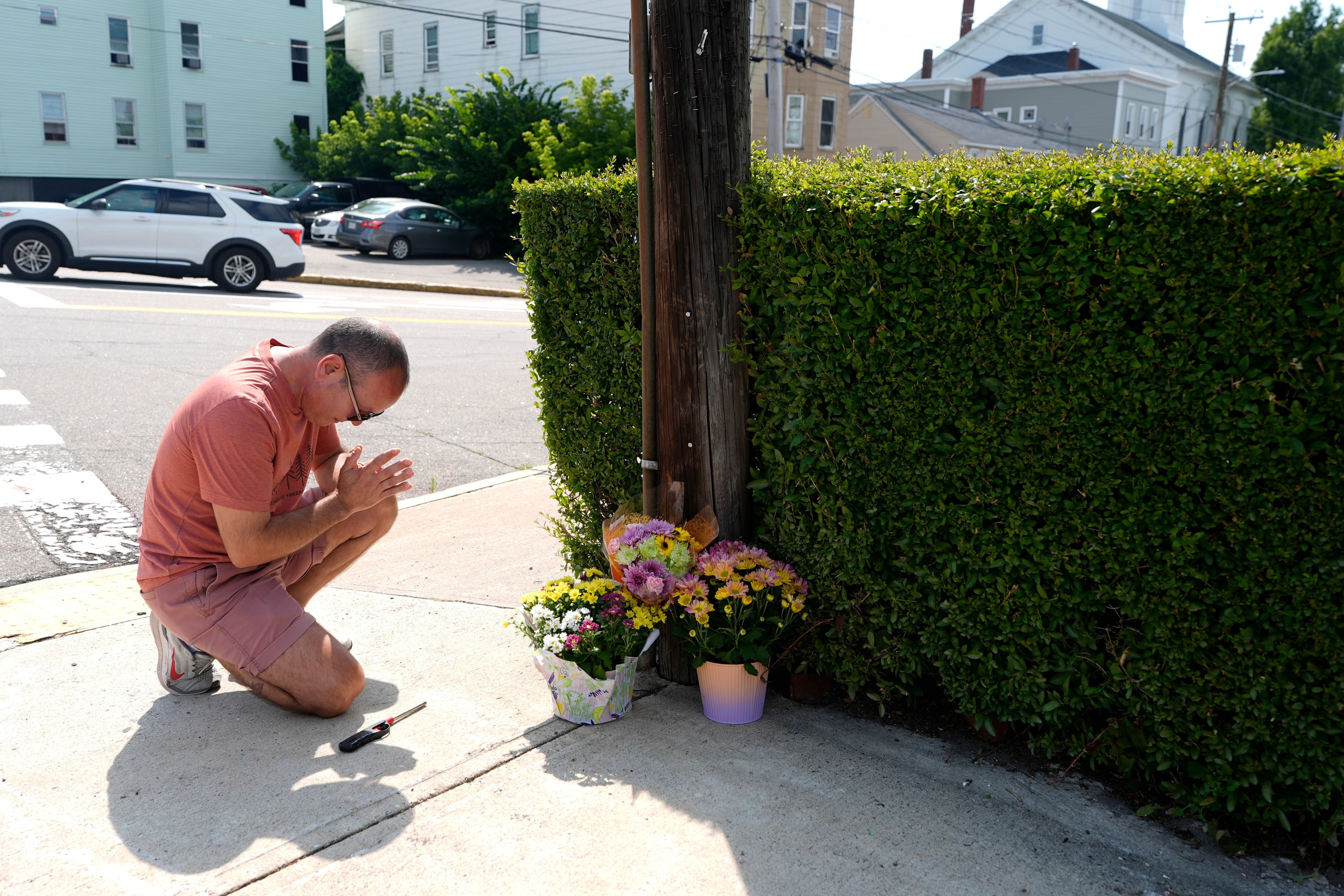 Misael Valdez se arrodilla cerca de unas flores colocadas en la intersección donde ocurrieron disparos con participación del Servicio de Inmigración y Control de Aduanas de Estados Unidos en Biddeford, Maine.