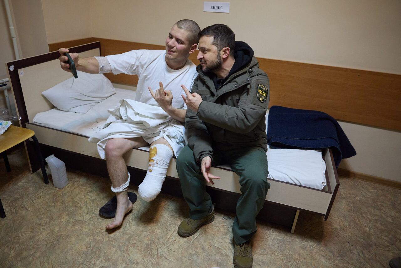 Esta foto del folleto, tomada y publicada por el servicio de prensa presidencial de Ucrania el 6 de diciembre de 2022, muestra al presidente ucraniano Volodymyr Zelensky (derecha) posando para una foto con un soldado ucraniano herido en un hospital durante su visita a la región de Kharkiv en medio de la invasión rusa de Ucrania. . - El presidente Volodymyr Zelensky visitó el 6 de diciembre de 2022 la región de primera línea de Donetsk en el este de Ucrania y describió los combates en el área como "difíciles" con las fuerzas rusas presionando para capturar la ciudad industrial de Bakhmut. (Foto de STRINGER / SERVICIO DE PRENSA PRESIDENCIAL DE UCRANIA / AFP) / RESTRINGIDO A USO EDITORIAL - CRÉDITO OBLIGATORIO "FOTO AFP / Servicio de prensa presidencial de Ucrania" - SIN MARKETING SIN CAMPAÑAS PUBLICITARIAS - DISTRIBUIDO COMO SERVICIO A LOS CLIENTES