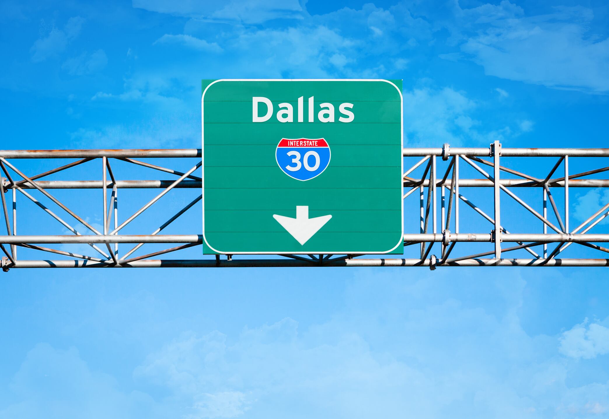 An elevated overhead highway sign. It reads "Dallas" and has an Interstate 30 shield above an arrow pointing downward.