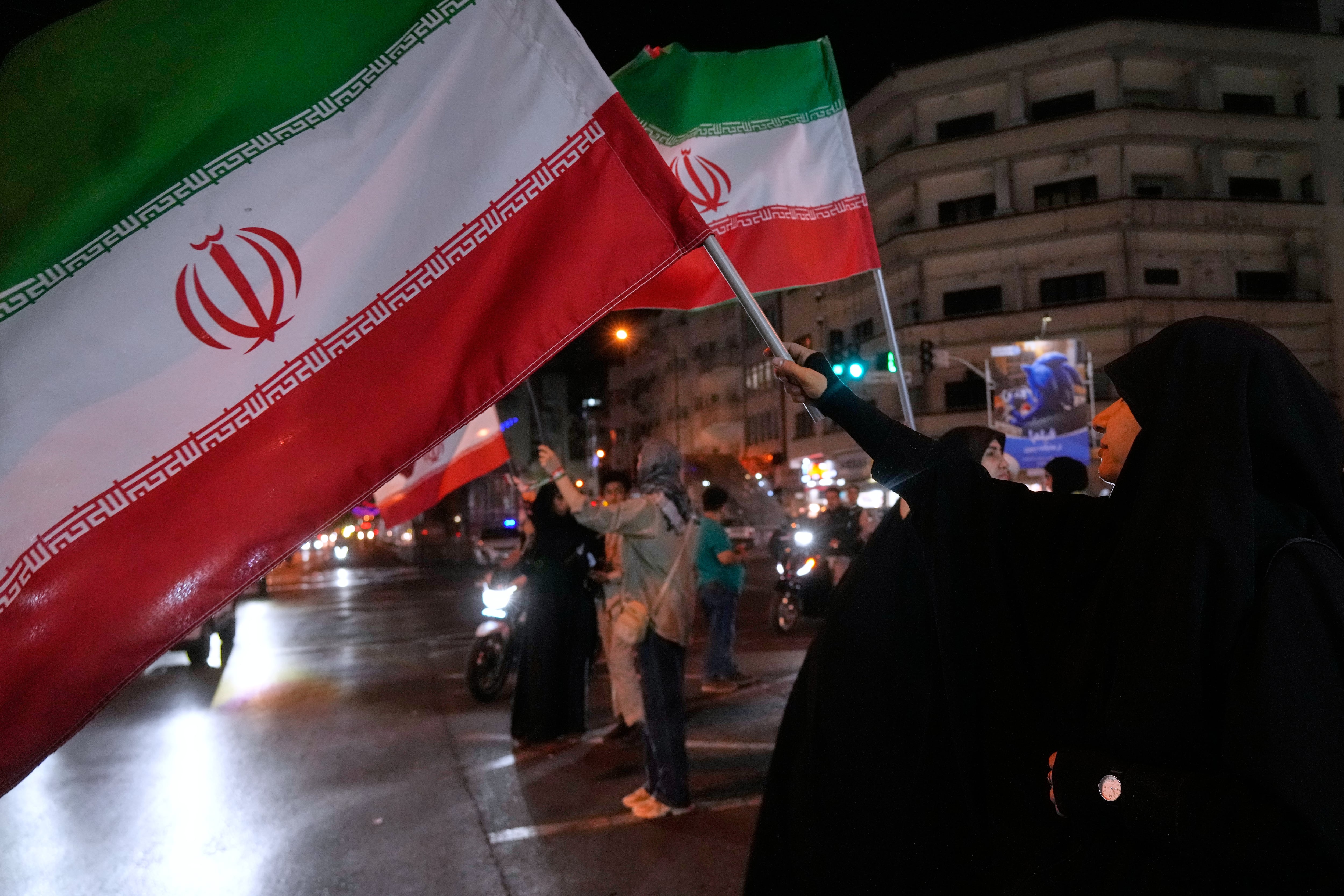 Mujeres portan banderas iraníes en una campaña a favor del gobierno en el centro de Teherán, Irán.