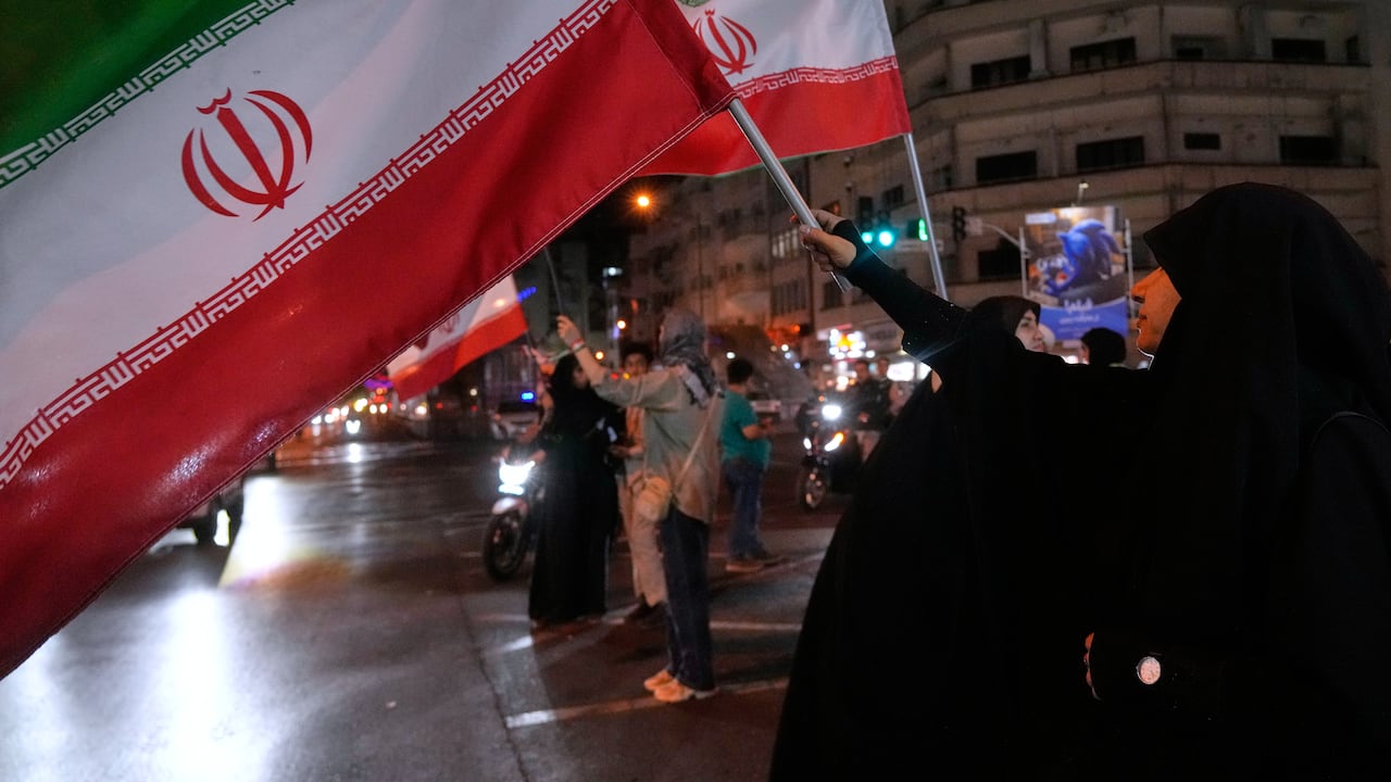 Mujeres portan banderas iraníes en una campaña a favor del gobierno en el centro de Teherán, Irán.