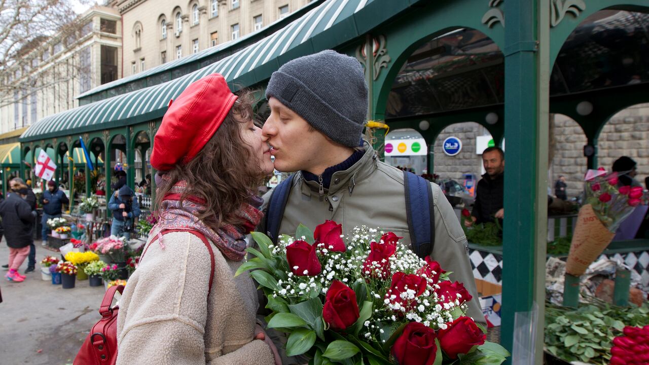 Una pareja comparte un tierno momento cerca de un mercado de flores que celebra el Día Internacional de la Mujer en Tiflis, Georgia, el martes 8 de marzo de 2022. (AP Photo/Shakh Aivazov)