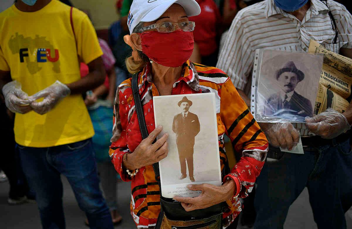Esta mujer, con tapabocas debido a la pandemia de covid-19, sostiene una foto del doctor venezolano José Gregorio Hernández, durante la inauguración de su monumento restaurado. Se trata de un mural cerca del sitio donde murió, en el barrio de La Pastora de Caracas. El papa Francisco aprobó el 19 de junio de 2020 la beatificación de Hernández, conocido como el "médico de los pobres". Foto: Matias Delacroix / AP