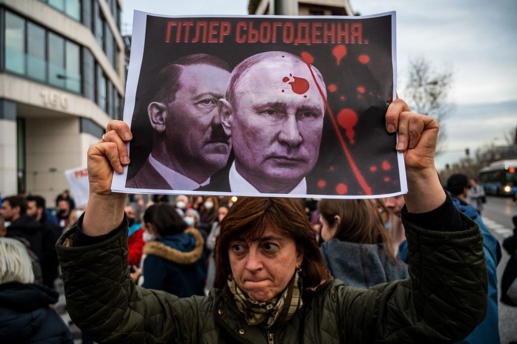 Una mujer es vista con un cartel que muestra las imágenes de Putin y Hitler durante una protesta después de los primeros ataques rusos registrados en Ucrania. Los ucranianos residentes en Madrid se concentraron, el 24 de febrero de 2022, frente a la embajada rusa para protestar contra los ataques rusos registrados en varios puntos del país ucraniano exigiendo el fin de la guerra y gritando consignas contra el presidente ruso Vladimir Putin. (Foto de Marcos del Mazo/LightRocket vía Getty Images)