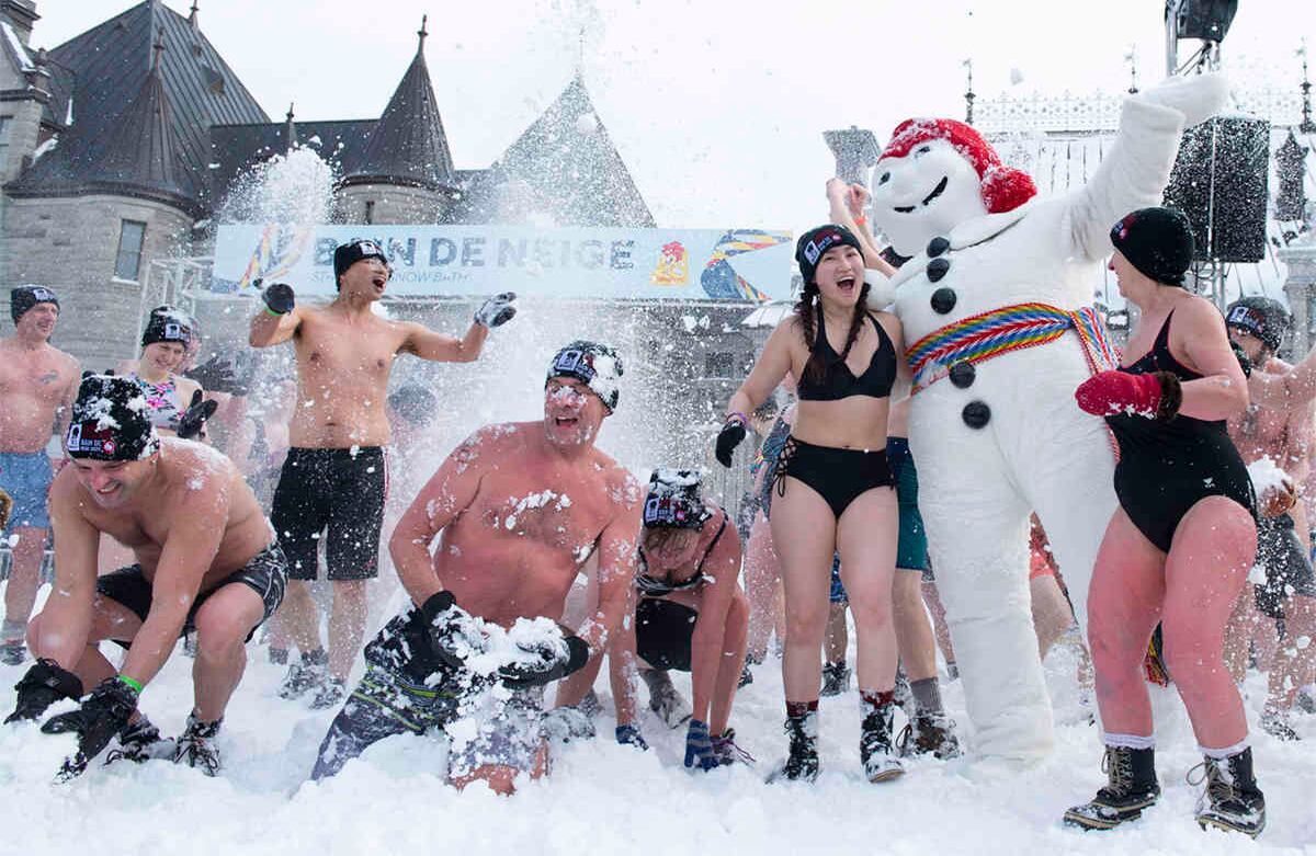 Bañistas  juegan en la nieve con Bonhomme, el representante oficial del carnaval de invierno de Quebec, ciudad canadiense mayoritariamente francófona. Toma del 16 de febrero de 2020. Foto: Jacques Boissinot / AP. 