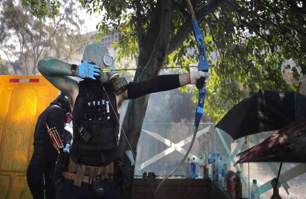 Un hombre se prepara para disparar una flecha contra la Fuerza pública de Hong Kong. La angustia se toma las calles de la ciudad. Foto: AP/Kin Cheung.