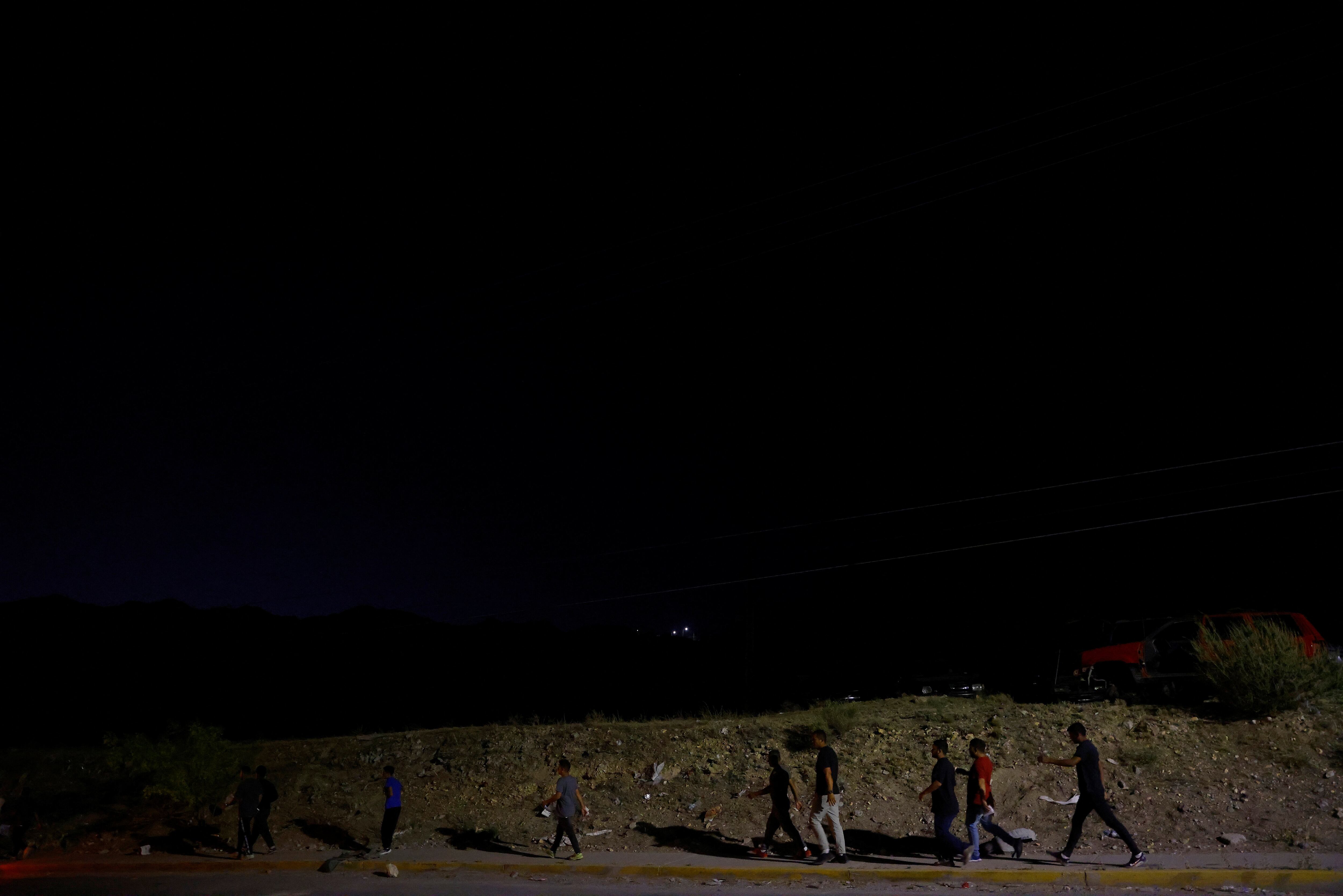 Migrantes , que fueron expulsados ​​de Estados Unidos a México bajo el Título 42 a través del puerto fronterizo internacional Jerónimo-Santa Teresa, caminan en un barrio en las afueras de Ciudad Juárez, México.