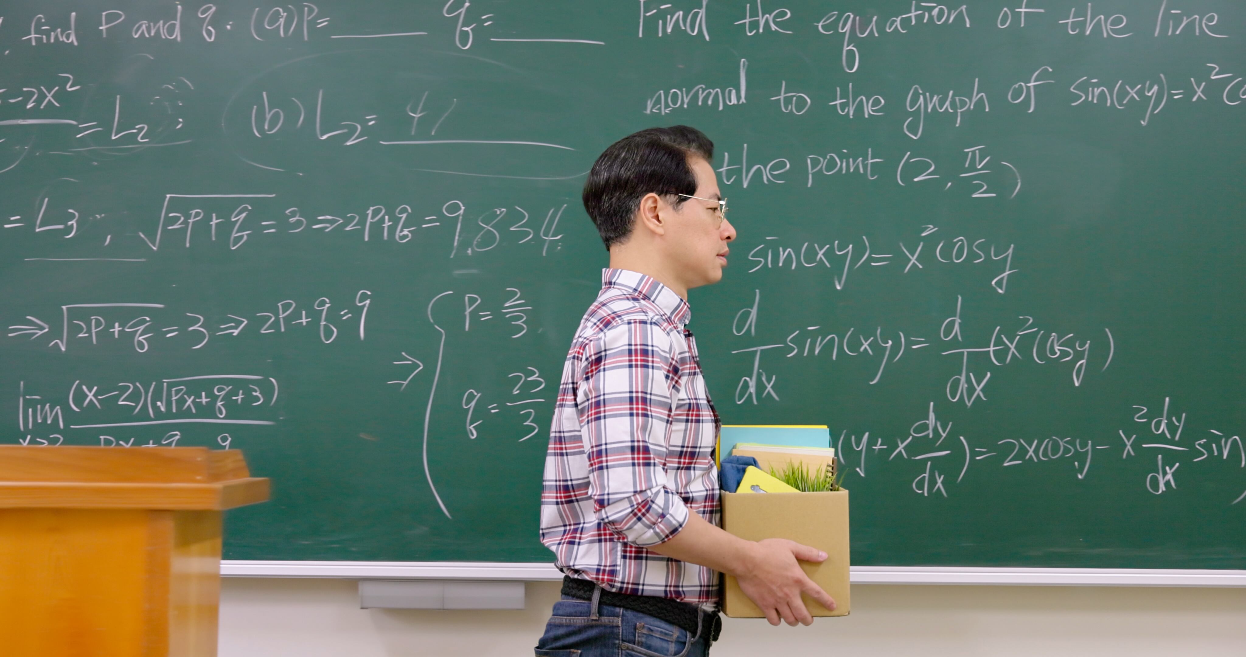 Sostiene una caja al salir del aula universitaria.