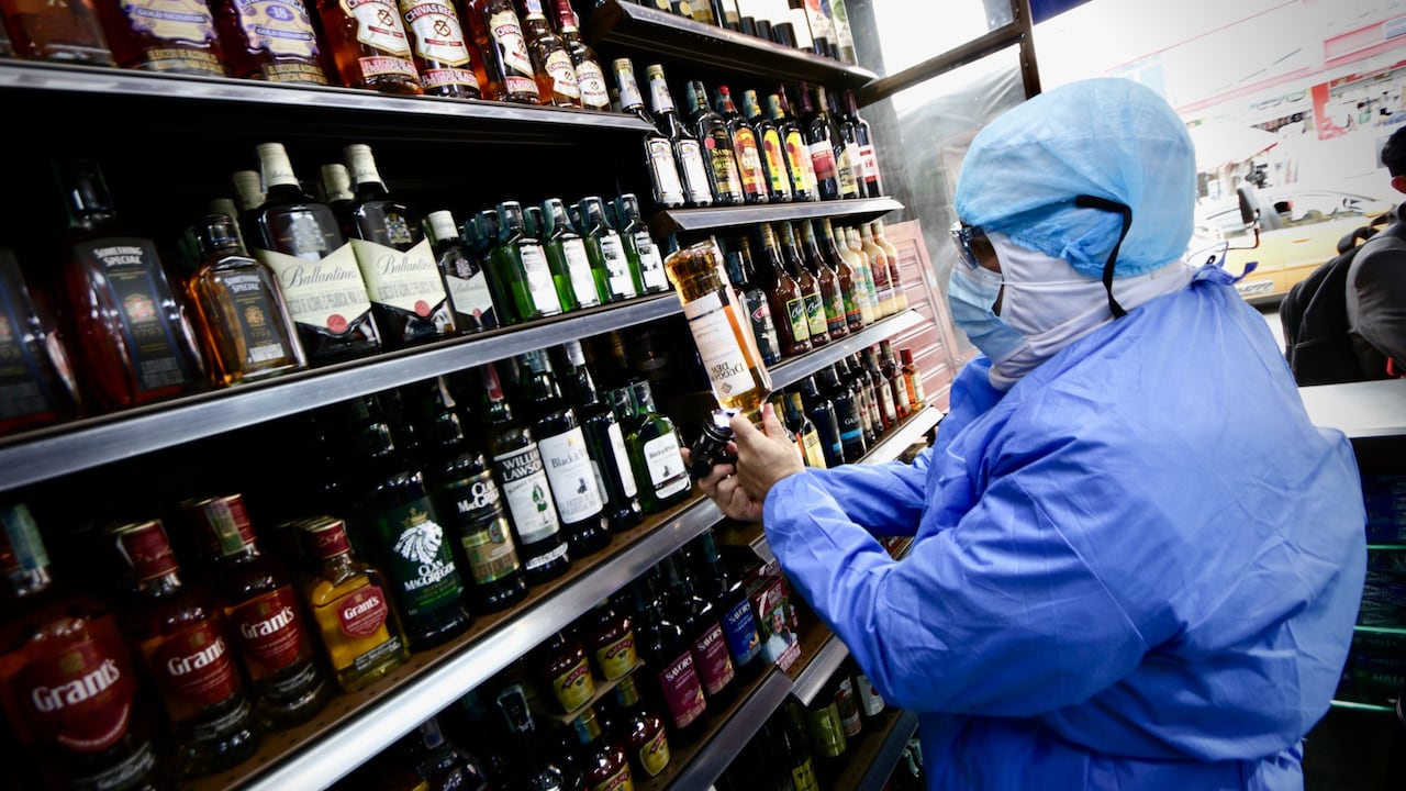 Funcionaria de la Secretaría de Salud inspeccionando botellas de licor para Halloween.
