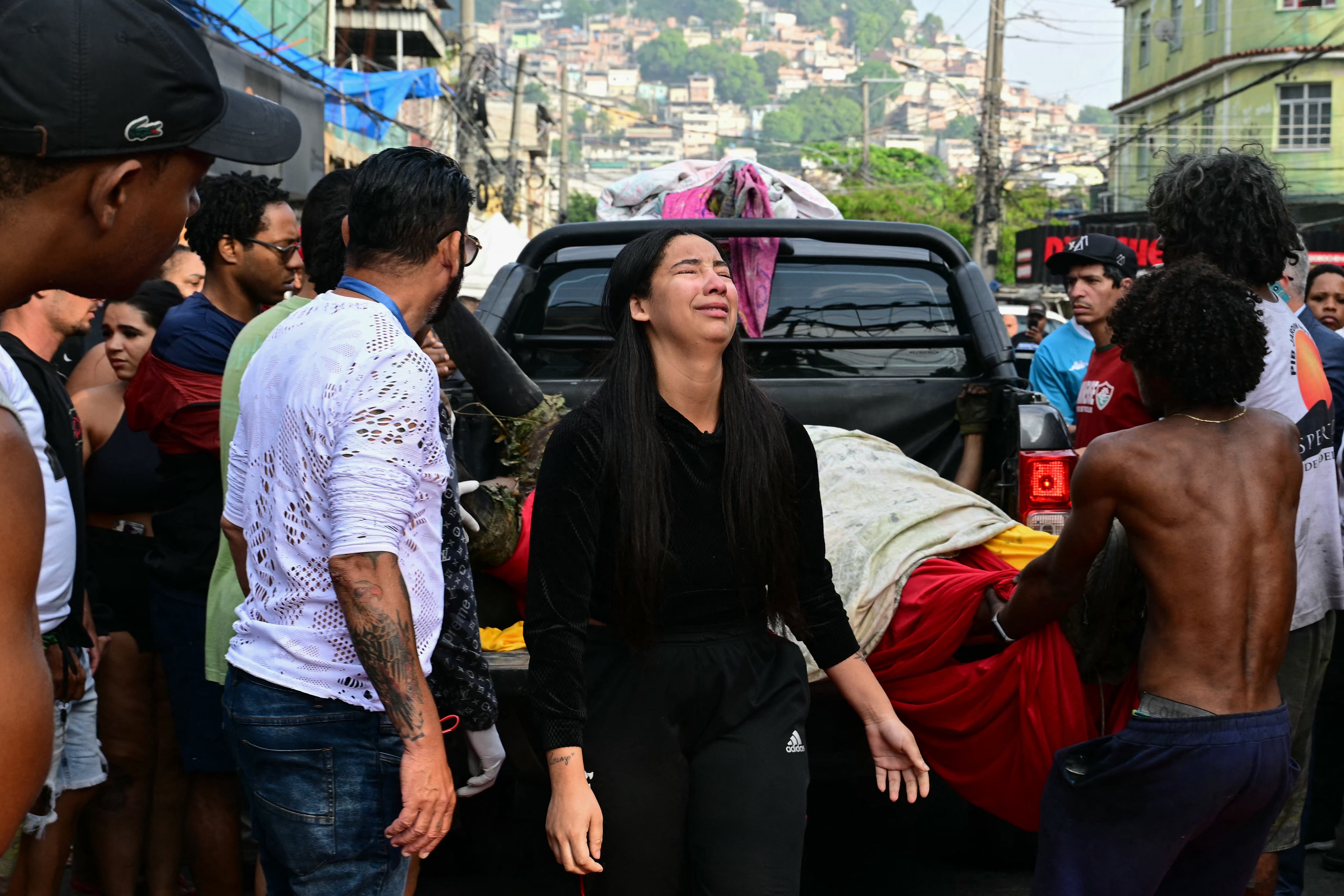 Una mujer llora mientras descargan cadáveres de una camioneta en la plaza São Lucas de la favela Vila Cruzeiro, en el complejo Penha de Río de Janeiro, Brasil, esto tras la Operación Contención.   (Photo by Pablo PORCIUNCULA / AFP)