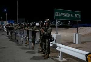 Peruvian police in riot gear guard the border between Chile and Peru, Thursday, April 27, 2023. A migration crisis at the border between Chile and Peru is intensifying, with hundreds of people stranded, unable to cross into Peru in an effort to return to their homes, as the mostly Venezuelan migrants seek to cross into Peru to continue on to their home country but Peru isn't allowing them to enter because they lack documents. (AP Photo/Martin Mejia)