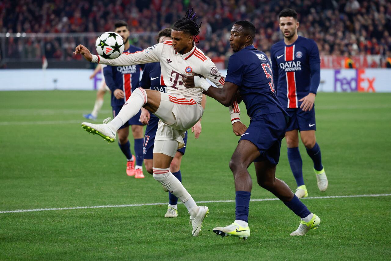 El mediocampista francés del Bayern Munich #17 Michael Olise (L) y el defensor ecuatoriano #51 del Paris Saint-Germain Willian Pacho compiten por el balón.