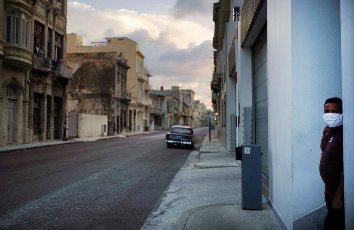 Un hombre que lleva una máscara como medida de precaución contra la propagación del nuevo coronavirus se encuentra en el marco de una puerta junto a una calle vacía durante el toque de queda en La Habana, Cuba, el martes 1 de septiembre de 2020. Las autoridades cubanas iniciaron un estricto bloqueo de 15 días en La Habana para acabar con la propagación de bajo nivel, pero persistente del nuevo coronavirus en la capital. Foto: Ramón Espinosa / AP