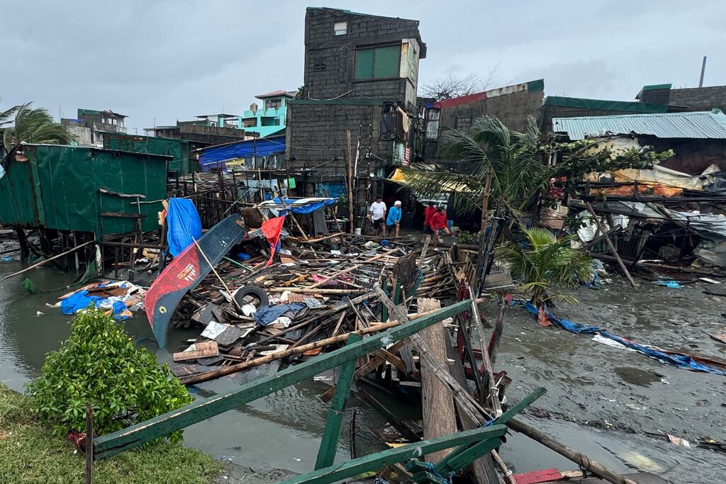 Residentes se encuentran junto a una casa dañada y un puente derribado por el tifón Fung-wong en un pueblo costero el lunes 10 de noviembre de 2025 en Navotas, Filipinas. (Foto AP/Aaron Favila)