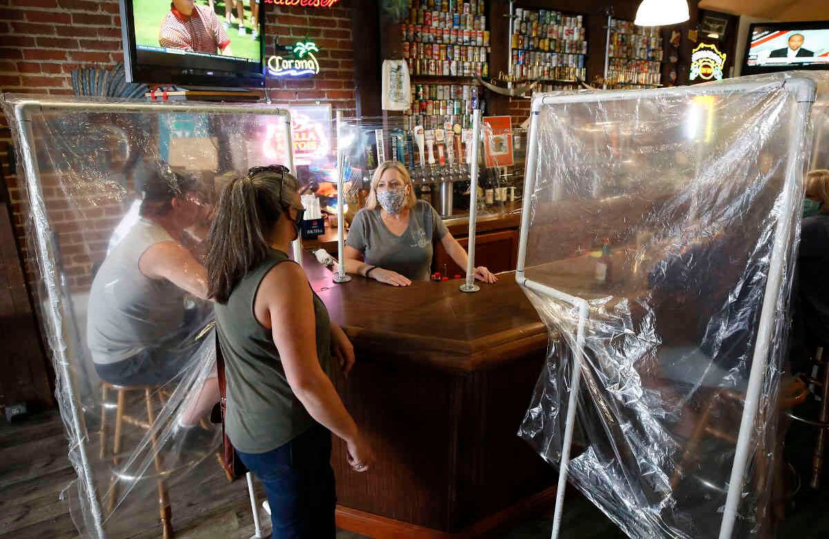  En esta foto de archivo del miércoles 13 de mayo de 2020, Sheila Kelly, propietaria del bar Powell's Steamer Co. & Pub, ayuda a los clientes en su restaurante, en la ciudad de Placerville, California, en el condado de El Dorado. Era el primer día que Kelly servía comidas desde la cuarentena. El condado fue uno de los primeros en obtener la aprobación del estado para reabrir. Foto: Rich Pedroncelli/ AP. 