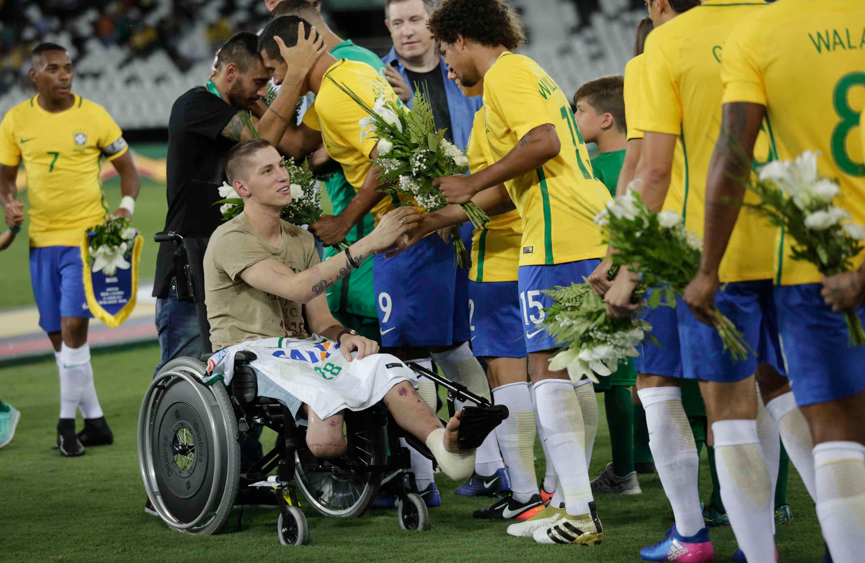 El ex arquero del Chapecoense Follmann, en silla de ruedas, y Alan Ruschel, detrás de él, saludan a los futbolistas brasileños antes de un partido amistoso con Colombia en el estadio Nilton Santos, en Río de Janeiro, Brasil, el miércoles 25 de enero de 2017. El partido es fue en homenaje a los jugadores del Chapecoense que murieron en un accidente aéreo en Colombia en noviembre pasado. Follmann y Ruschel sobrevivieron al choque. (AP Photo / Silvia Izquierdo)