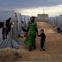 Una madre kurda camina con su hijo en un campo de refugiados cerca de la frontera entre Siria y Turquía. Foto: Gokhan Sahin/Getty Images.