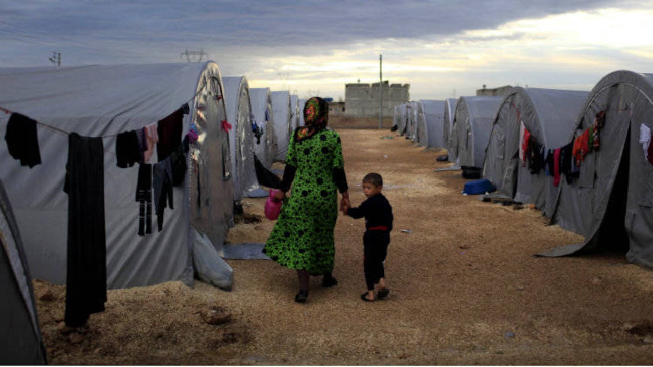 Una madre kurda camina con su hijo en un campo de refugiados cerca de la frontera entre Siria y Turquía. Foto: Gokhan Sahin/Getty Images.