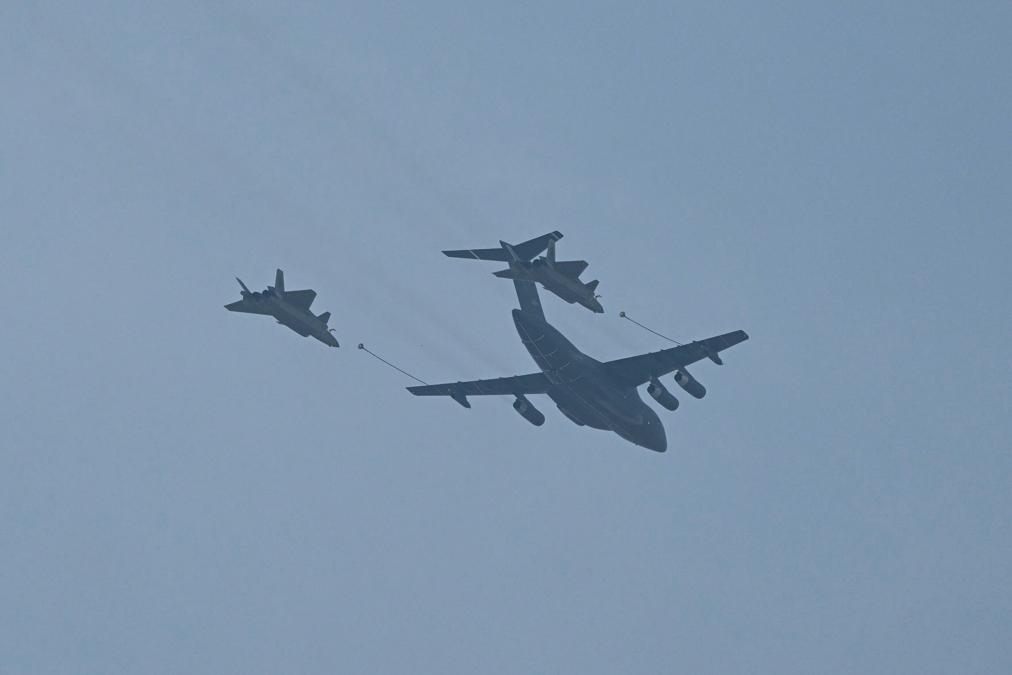 Un avión Xi'an Y-20 Kunpeng y dos aviones de combate Chengdu j-20 Mighty Dragon realizan una maniobra de reabastecimiento de combustible en el aire durante un desfile militar que marca el 80 aniversario de la victoria sobre Japón y el fin de la Segunda Guerra Mundial, en la Plaza de Tiananmen de Beijing el 3 de septiembre de 2025. (Foto de GREG BAKER / AFP)
