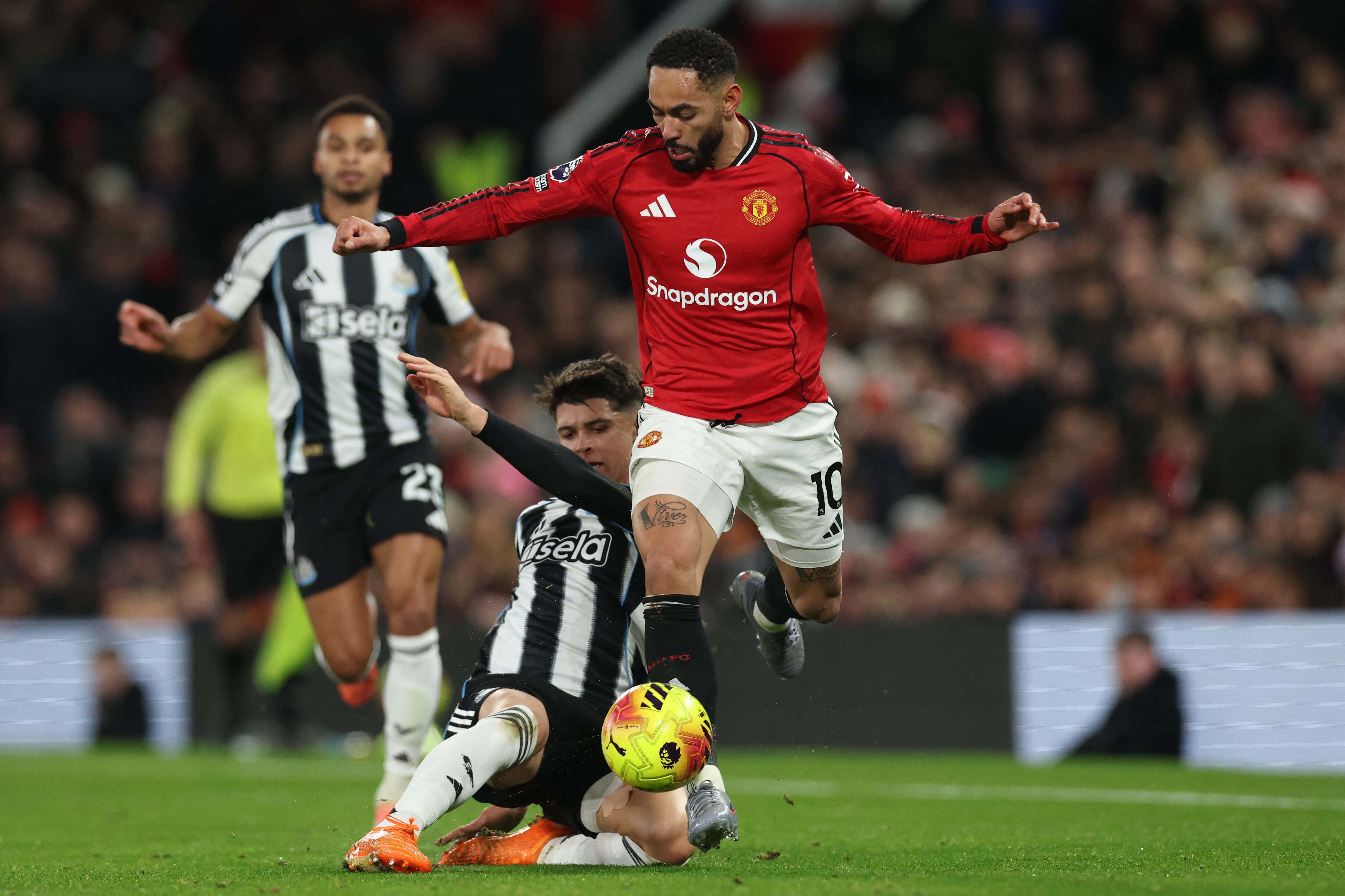 El centrocampista inglés del Newcastle United, Lewis Miley (izq.), compite con el delantero brasileño del Manchester United, Matheus Cunha (der.), durante el partido de la Premier League inglesa entre el Manchester United y el Newcastle United en Old Trafford, en Manchester, noroeste de Inglaterra, el 26 de diciembre de 2025. (Foto de Darren Staples / AFP)