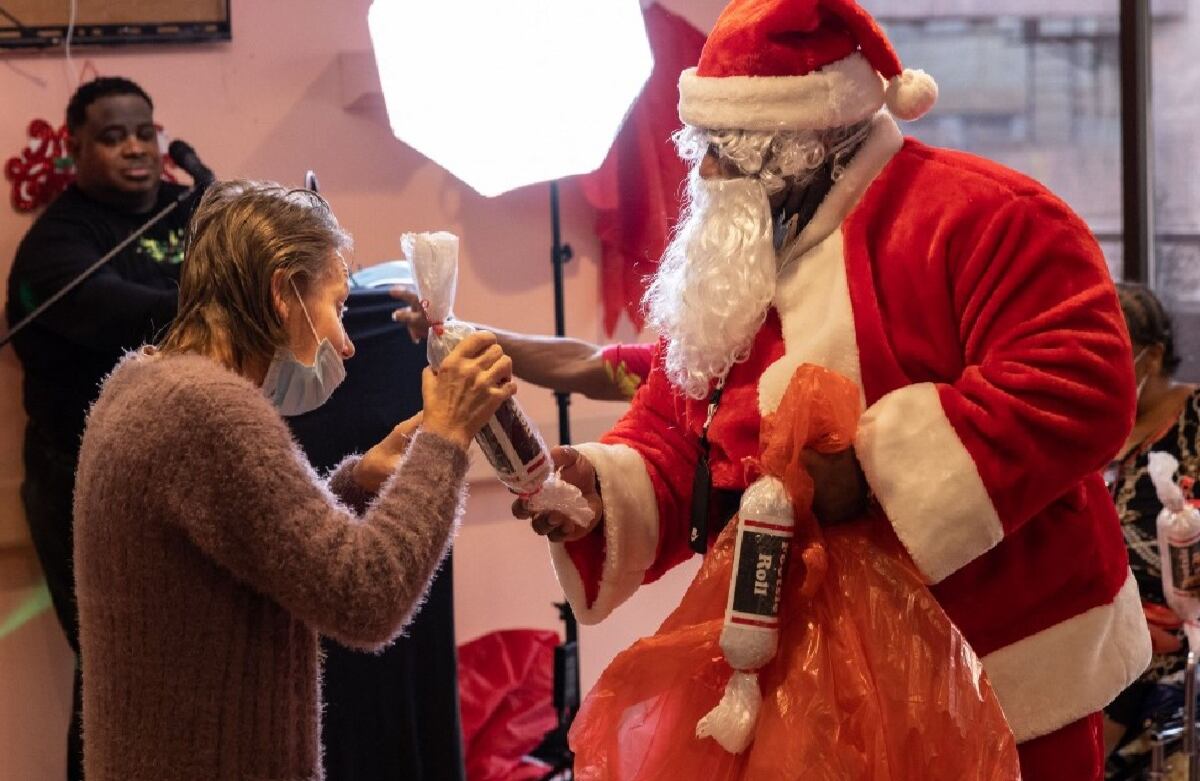 Un hombre vestido como Papá Noel entrega un obsequio a una mujer en un asilo de ancianos, en la ciudad de Nueva York.